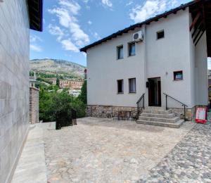 a white house with a stone patio with stairs at Pansion Villa Nur in Mostar