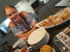 Une femme se tient derrière un comptoir avec de la nourriture dans l'établissement Kotkan Residenssi Guesthouse Huonemajoitus, à Kotka