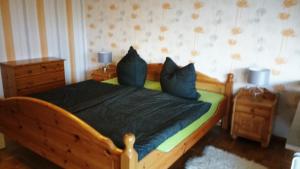 - une chambre avec un lit en bois et des oreillers bleus dans l'établissement Ferienwohnung Rhododendron - Natur pur am Highwalk, à Rotenburg an der Fulda 25 autres photos