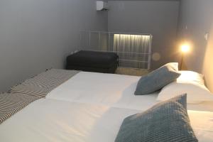 a bedroom with a white bed and a black chair at StayInn City - Póvoa de Varzim in Póvoa de Varzim