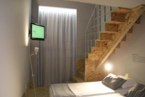 a bedroom with a bed with a television and a staircase at StayInn City - Póvoa de Varzim in Póvoa de Varzim