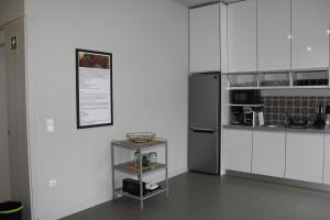 a kitchen with white cabinets and a silver refrigerator at StayInn City - Póvoa de Varzim in Póvoa de Varzim