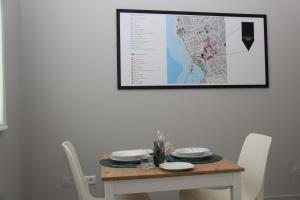 a table with white chairs and a picture on the wall at StayInn City - Póvoa de Varzim in Póvoa de Varzim