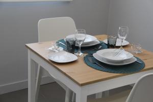 a wooden table with plates and wine glasses on it at StayInn City - Póvoa de Varzim in Póvoa de Varzim