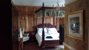 a bedroom with a canopy bed and a chair at Neuadd Arms Hotel in Llanwrtyd Wells