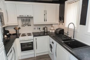 a kitchen with white cabinets and a sink at Silver Key Apartments in Inverness +18 photos