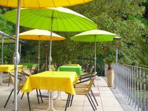 a patio with tables and chairs with green and yellow umbrellas at Gasthof zum Lahntal in Laurenburg