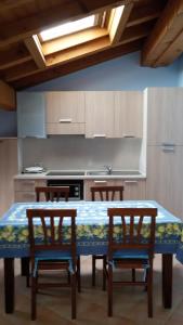 una cucina con tavolo con 4 sedie e una cucina con piano cottura di Mansarda Ariel a Limone sul Garda