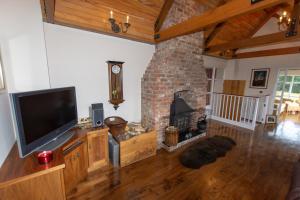 sala de estar con TV y chimenea de ladrillo en Pellipar Gatelodge, en Bovevagh