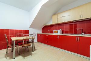 a kitchen with red cabinets and a table and chairs at Pensiunea Arthur in Râmnicu Vâlcea