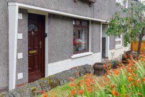 a house with a brown door and flowers in front of it at Lomond Serviced Apartments- Inglewood in Alloa