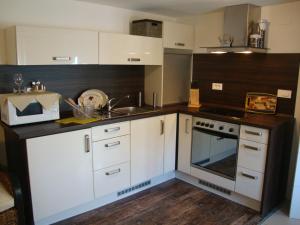 a kitchen with white cabinets and a sink and an oven at Apartments Ilona in Novi Vinodolski