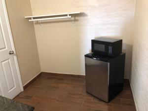a microwave on top of a refrigerator in a room at Buckboard Motel in Santa Maria