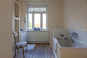 a bathroom with a tub and a chair and a window at B&B mybandb in Bruges