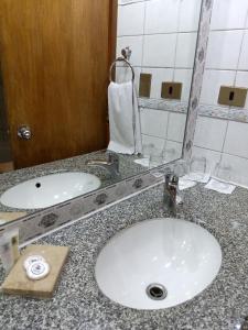 a white sink sitting under a mirror in a bathroom at Windsor Suites Hotel in Santiago