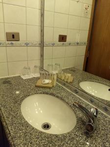 a bathroom with a sink, mirror, and soap dispenser at Windsor Suites Hotel in Santiago