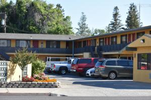 a hotel with cars parked in a parking lot at Apex Inn in Modesto