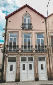 ein rosafarbenes Gebäude mit weißen Türen und Fenstern in der Unterkunft Porto Luxury Apartments in Vila Nova de Gaia
