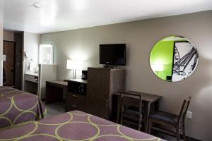 a living room with a television and a bed at Super 8 by Wyndham Waxahachie TX in Waxahachie