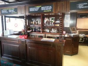 um bar com armários de madeira e garrafas de álcool em The Windsor Hotel em Whitley Bay
