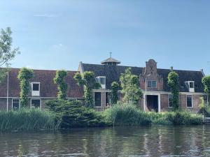 ein altes Haus am Ufer eines Flusses in der Unterkunft HUISJES AAN DE AMSTEL - Your home away from home in Amstelveen