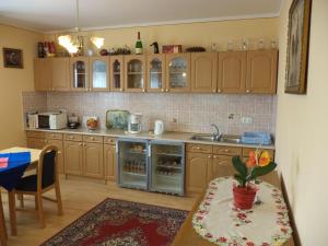 a kitchen with wooden cabinets and a table and a sink at Herkules Panzió in Nagykanizsa
