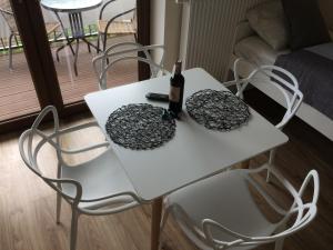 a white table with a bottle of wine and two chairs at Apartament Fibra Latte in Rybnik