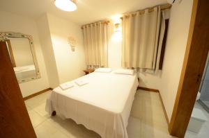 sypialnia z białym łóżkiem i lustrem w obiekcie Pousada Ana do Forte w mieście Praia do Forte