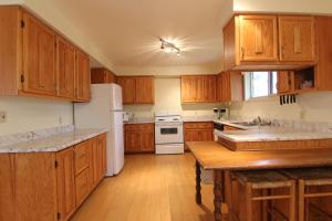 cocina con armarios de madera y nevera blanca en Birch Cliff Lodge on Baptiste Lake, en Bancroft