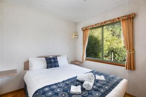 a bedroom with a bed and a window at Enclave at Healesville Holiday Park in Healesville