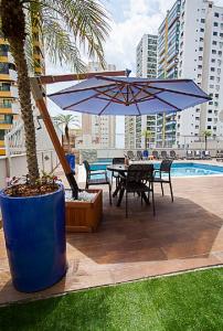 um pátio com uma mesa e um guarda-chuva azul em Hotel Sibara SPA & Convenções em Balneário Camboriú
