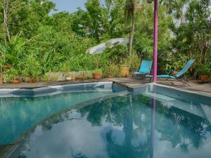 a swimming pool with two chairs and an umbrella at Le Parc aux Orchidées in Pointe-Noire