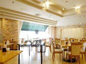a restaurant with tables and chairs and a brick wall at Mito Keisei Hotel in Mito