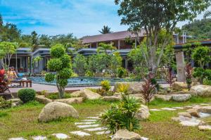 a garden in front of a house with a swimming pool at Wang Sai Resort - SHA Plus in Mae Haad