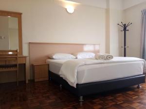 a bedroom with a bed with white sheets and a dresser at Lumut Valley Condominium in Lumut