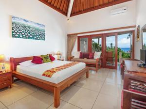 a bedroom with a bed and a table and a desk at Villa Pantai Candidasa by Villa Finder in Candidasa