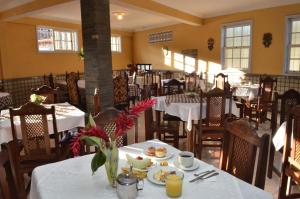 a dining room with tables and chairs with plates of food at Hotel Priskar in Ouro Preto