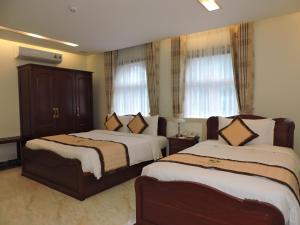 a hotel room with two beds and two windows at Minh Tam Phu Nhuan Hotel & Spa in Ho Chi Minh City