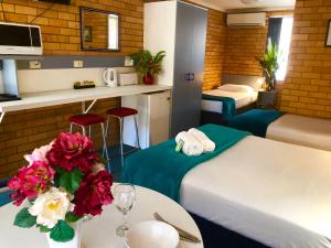 una habitación de hotel con 2 camas y una mesa con flores en Bosuns Inn Motel, en Coffs Harbour
