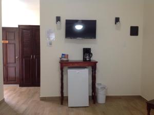 Habitación con mesa pequeña y TV en la pared. en Jan's Hotel, en Caye Caulker