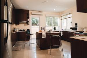 a kitchen with dark brown cabinets and bar stools at Green Olive Villa Amata Spring Golf in Ban Nong Mai Daeng (2)