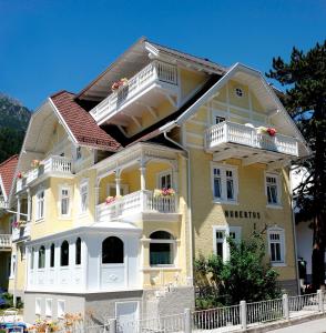 une maison jaune avec des balcons blancs dans une rue dans l'établissement Hotel Garni Hubertus-Nostalgie & Charme, à Fulpmes