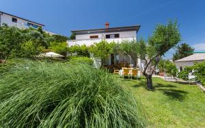 a house on a hill with tall grass at Apartman Maledi in Baška