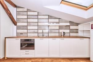 kuchnia z białymi szafkami i ścianą wyłożoną kafelkami w obiekcie Chodkiewicza 10 (A) - cozy studio by Homeprime w Krakowie