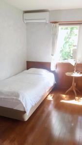 a bedroom with a bed and a window and a table at Cottage Ginkai Fuji in Yamanakako