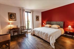 a bedroom with a red wall with a bed and a desk at Clos Des Aspres in Ortaffa