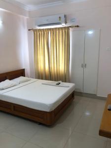a bedroom with a bed and a window with at Hotel GARISHPARK in Rāmanāthapuram