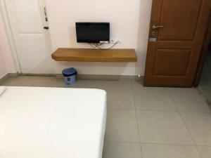 a room with a bed and a television on a wall at Hotel GARISHPARK in Rāmanāthapuram