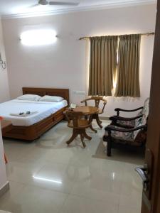 a bedroom with a bed and a table and a chair at Hotel GARISHPARK in Rāmanāthapuram
