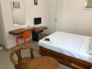 a bedroom with a desk and a bed and a chair at Hotel GARISHPARK in Rāmanāthapuram
